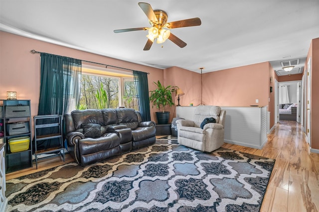 living room with wood finished floors, attic access, baseboards, visible vents, and a ceiling fan