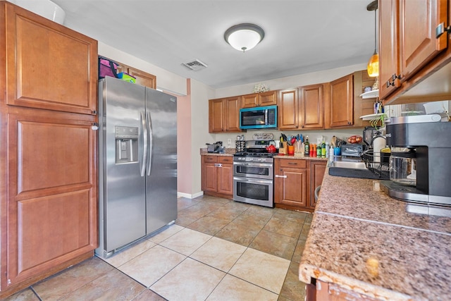 kitchen with brown cabinets, appliances with stainless steel finishes, visible vents, light countertops, and light tile patterned flooring