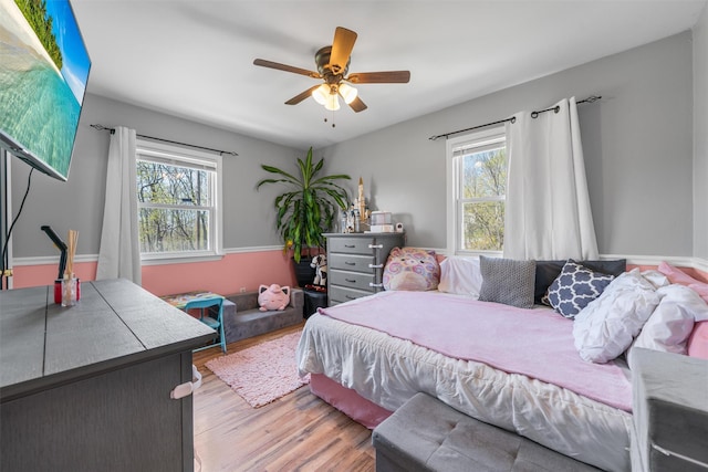 bedroom featuring wood finished floors, ceiling fan, and multiple windows