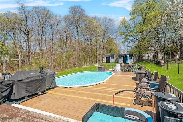 outdoor pool with an outdoor structure, a yard, a storage shed, area for grilling, and a deck