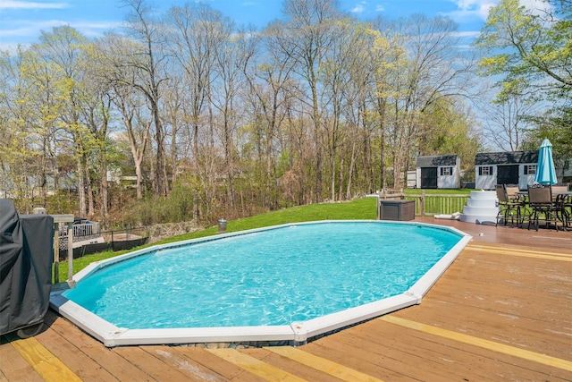 pool featuring an outbuilding, a shed, a deck, and outdoor dining space