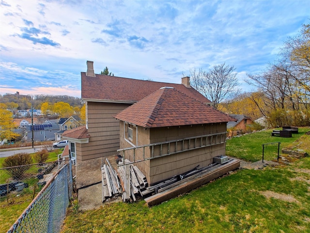 635 N Division St, Peekskill, NY 10566 - view of side of property featuring fence, roof with shingles, a chimney, and a lawn