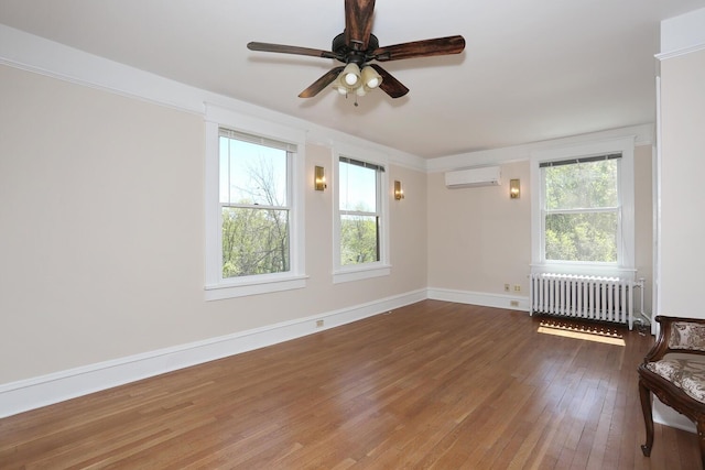 85 S Harrison Ave, Congers, NY 10920 - empty room featuring an AC wall unit, radiator, a wealth of natural light, and hardwood / wood-style flooring