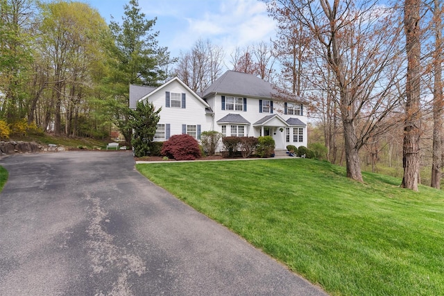 colonial-style house featuring a front lawn and driveway