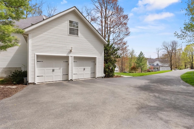 view of property exterior featuring an attached garage and aphalt driveway