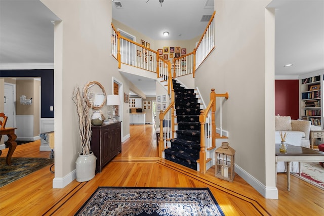 foyer entrance featuring stairway, baseboards, visible vents, and hardwood / wood-style flooring