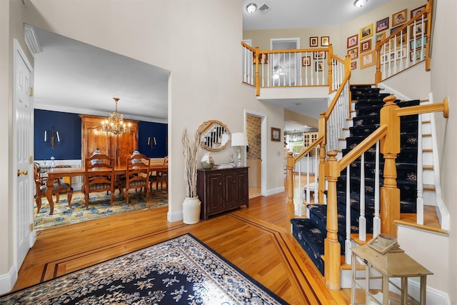 foyer entrance with baseboards, stairs, wood finished floors, and a chandelier