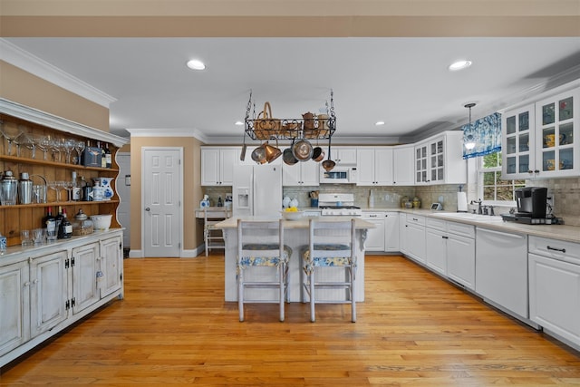 kitchen featuring ornamental molding, white cabinets, white appliances, and a kitchen bar
