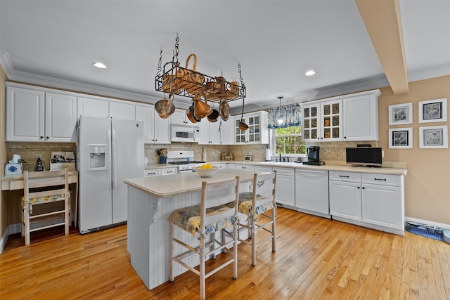 kitchen with white appliances, a kitchen breakfast bar, light countertops, tasteful backsplash, and glass insert cabinets