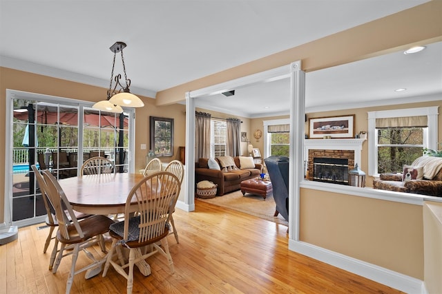 dining room with ornamental molding, a fireplace, baseboards, recessed lighting, and light wood-style flooring
