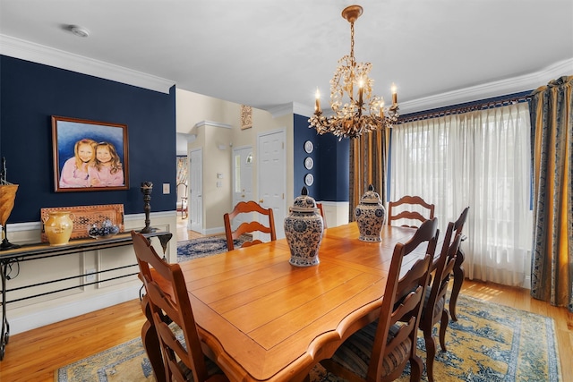 dining room featuring crown molding, light wood finished floors, a wainscoted wall, and an inviting chandelier