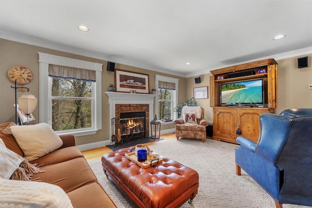living room with recessed lighting, ornamental molding, a wealth of natural light, and a stone fireplace