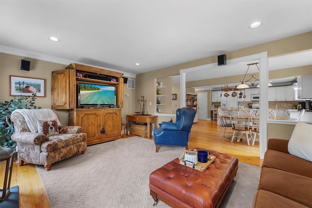 living room featuring recessed lighting, crown molding, and light wood-type flooring