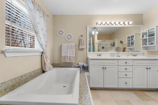bathroom featuring double vanity, a garden tub, a stall shower, a sink, and tile patterned floors