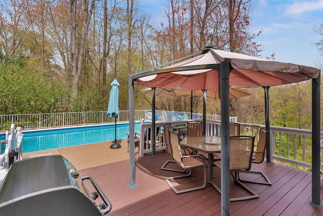 view of pool with fence, a fenced in pool, a wooden deck, and outdoor dining area