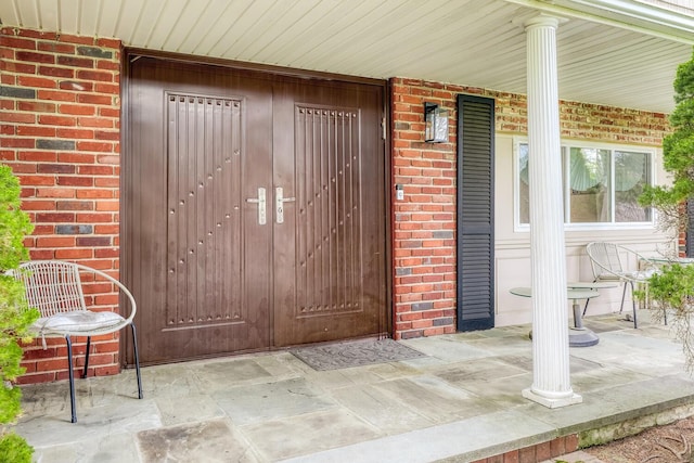 doorway to property with covered porch and brick siding