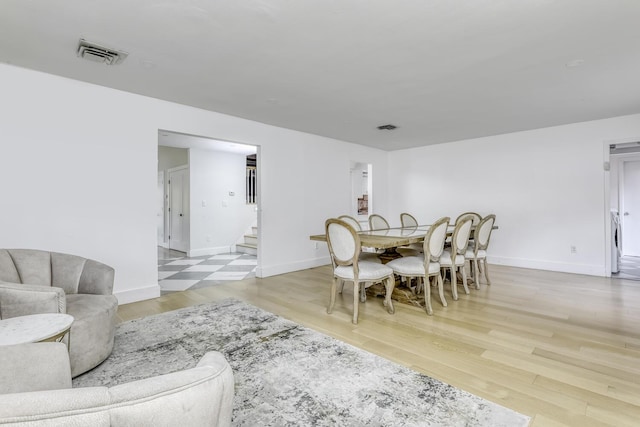 dining room featuring stairs, visible vents, wood finished floors, and baseboards