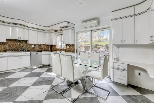 kitchen with appliances with stainless steel finishes, white cabinetry, a wall unit AC, and backsplash