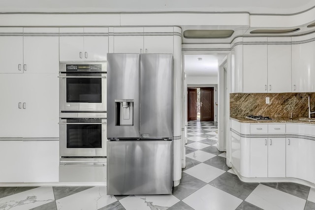 kitchen featuring appliances with stainless steel finishes, tasteful backsplash, stone countertops, and white cabinets