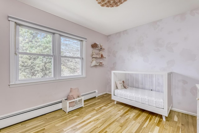 bedroom with wood finished floors, baseboard heating, and baseboards