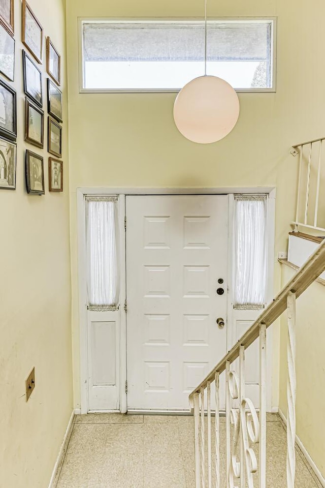 entryway with a towering ceiling, a wealth of natural light, and baseboards