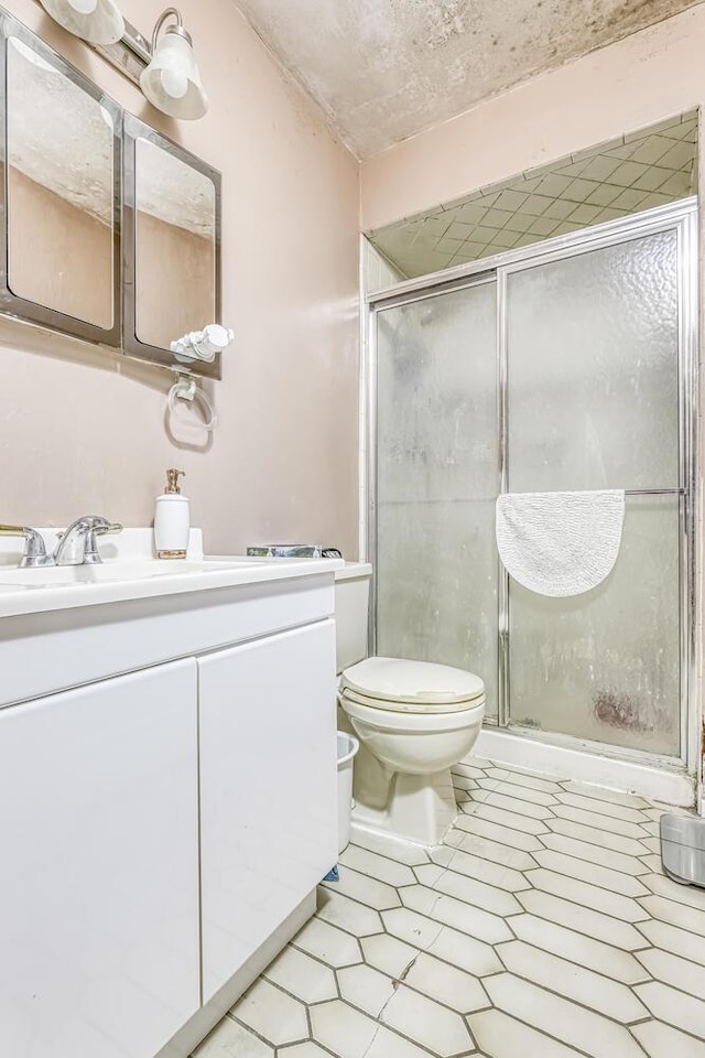 bathroom with tile patterned floors, a shower stall, toilet, and vanity