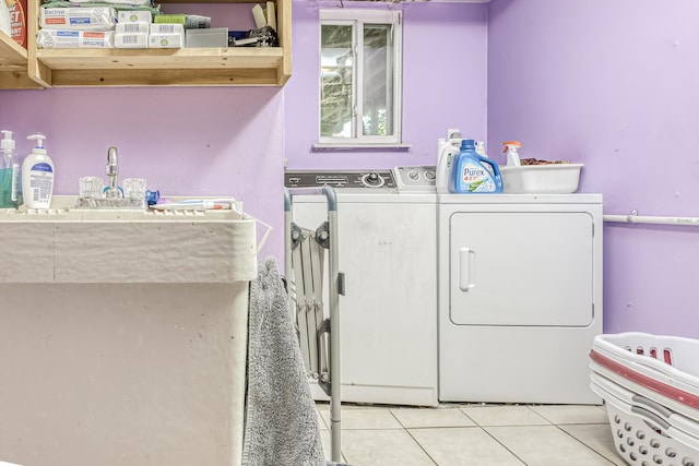 clothes washing area featuring light tile patterned floors, separate washer and dryer, and laundry area