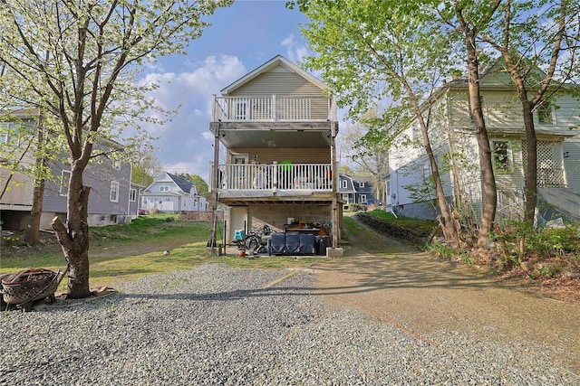 view of front of house with a fire pit, a carport, a residential view, driveway, and a balcony