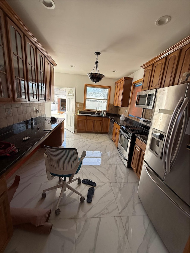kitchen with a sink, tasteful backsplash, marble finish floor, dark countertops, and appliances with stainless steel finishes