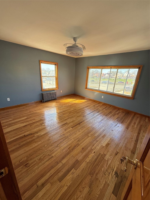 spare room with radiator heating unit, wood finished floors, and plenty of natural light