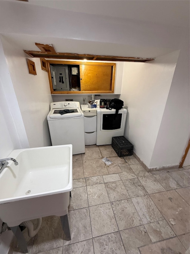 washroom with a sink, washing machine and dryer, electric panel, laundry area, and baseboards