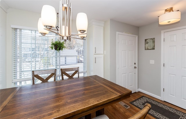 dining area with baseboards, visible vents, wood finished floors, and a notable chandelier