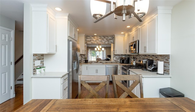 kitchen with decorative backsplash, white cabinets, a sink, stainless steel appliances, and recessed lighting