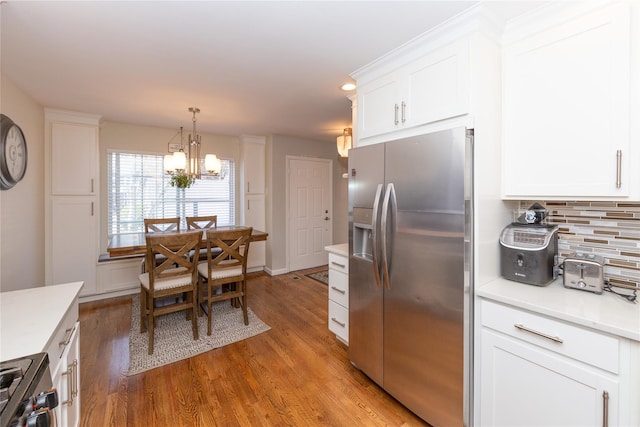 kitchen featuring stainless steel fridge, a notable chandelier, range, backsplash, and wood finished floors