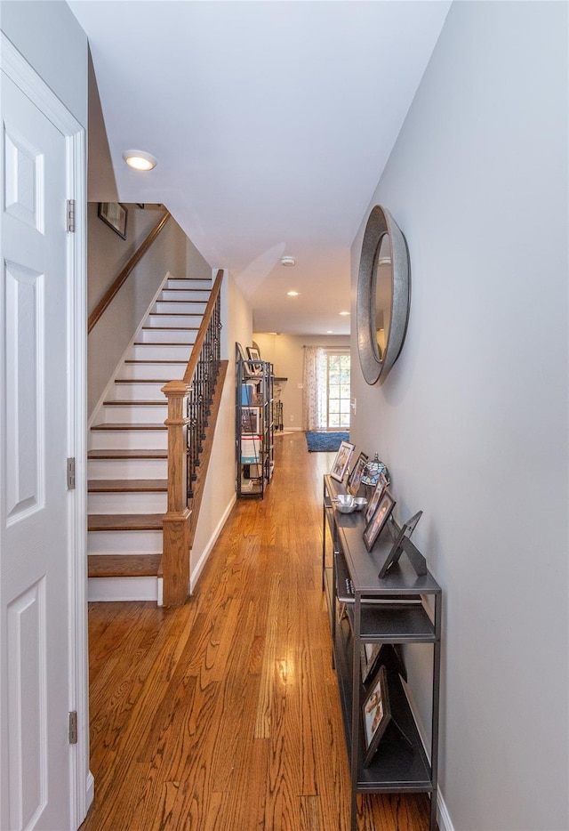 hall featuring recessed lighting, stairs, wood finished floors, and baseboards