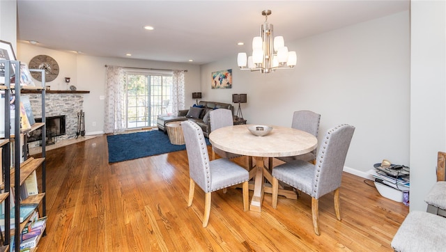 dining area with recessed lighting, an inviting chandelier, a fireplace with flush hearth, light wood-style flooring, and baseboards