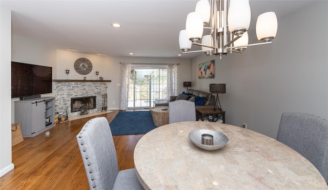 dining room featuring a fireplace, wood finished floors, recessed lighting, and a notable chandelier