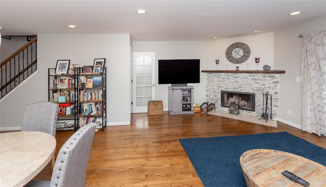 living room with a fireplace, wood finished floors, recessed lighting, and stairs