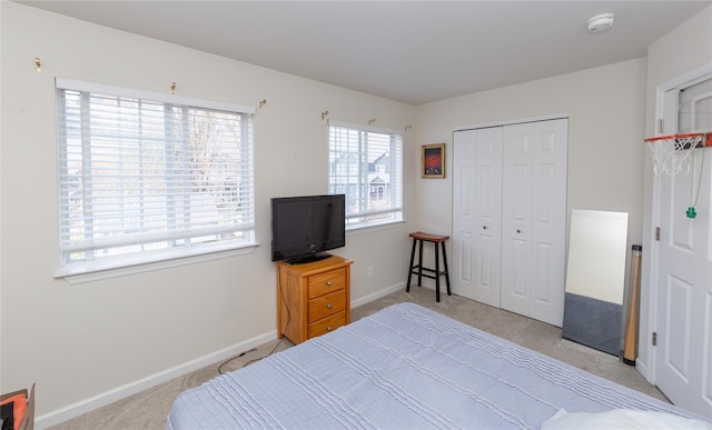 bedroom featuring baseboards, light carpet, and a closet