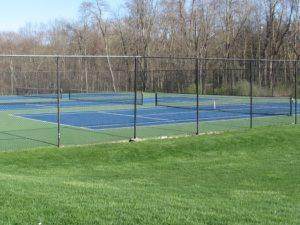 view of tennis court featuring a lawn and fence