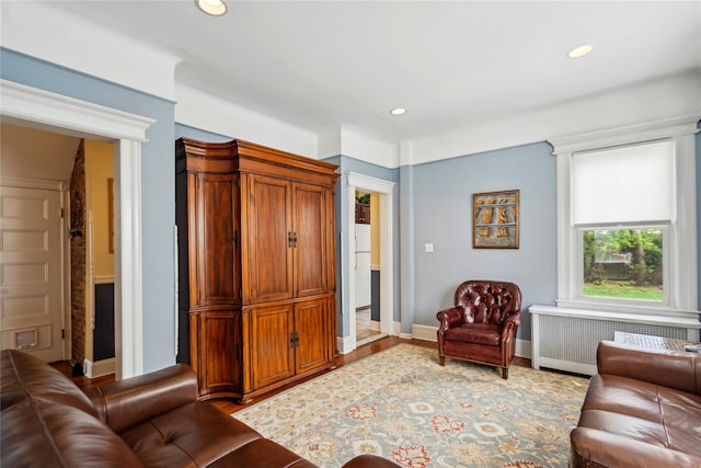 living area with recessed lighting, baseboards, radiator heating unit, and wood finished floors
