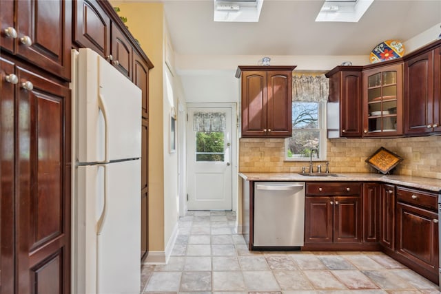 kitchen with a sink, dishwasher, freestanding refrigerator, backsplash, and a skylight