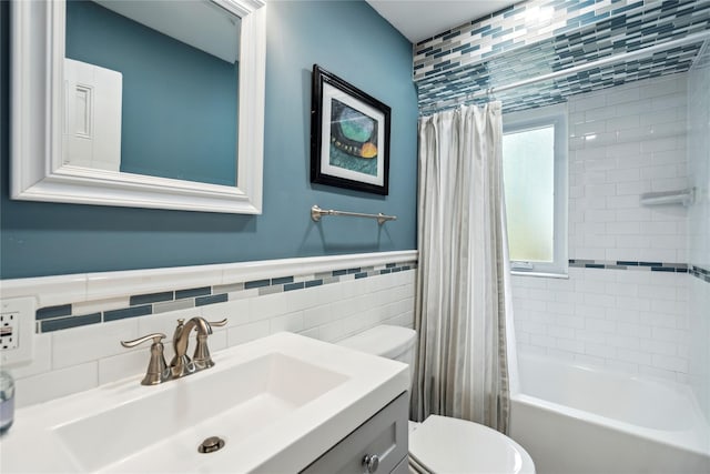 bathroom with shower / bath combo with shower curtain, vanity, wainscoting, toilet, and tile walls