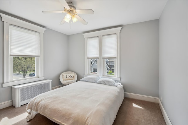 carpeted bedroom featuring radiator, baseboards, and multiple windows