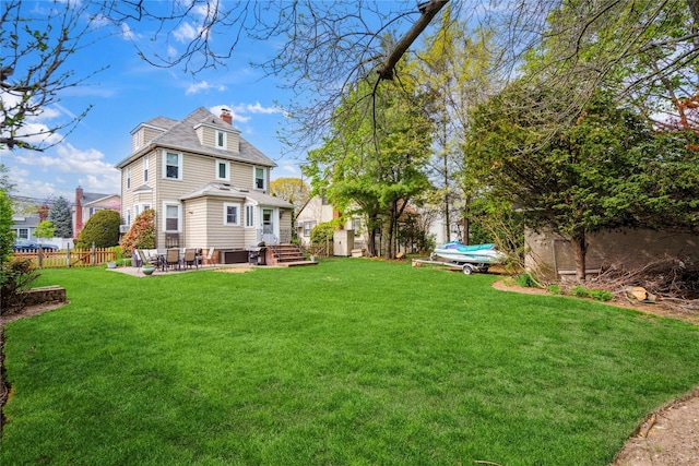 rear view of property with a patio, fence, a yard, and a chimney