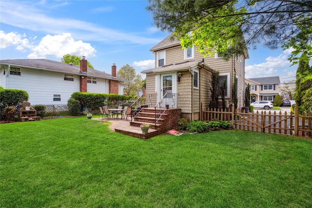 rear view of property featuring a lawn, fence, a chimney, and a patio