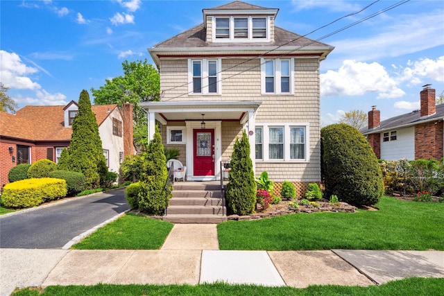 american foursquare style home featuring covered porch and a front yard