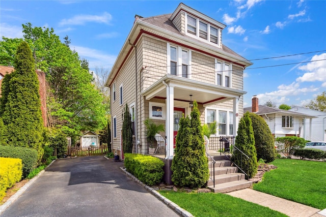 american foursquare style home with covered porch, driveway, and a front yard