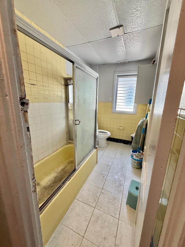 101-14 118th St, Richmond Hill S, NY 11419 - bathroom featuring tile walls, a wainscoted wall, toilet, tile patterned flooring, and bath / shower combo with glass door