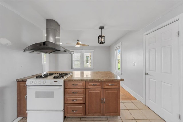 118 N Regent St, Port Chester, NY 10573 - kitchen with light tile patterned floors, brown cabinets, ceiling fan, island exhaust hood, and white range with gas stovetop
